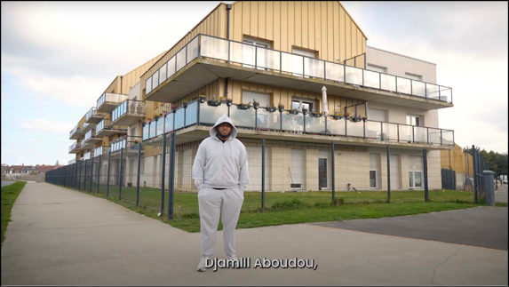 A man wearing a white hoodie stands in front of a building.

Contenu généré par l’IA