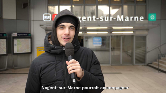 A man wearing a hooded jacket and a microphone is standing outside a building.

Contenu généré par l’IA