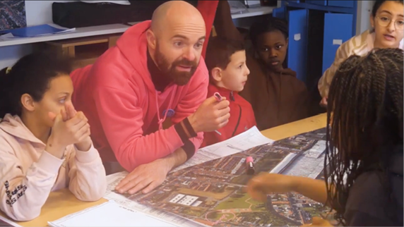 A group of people are sitting around a table, looking at a map. A man is pointing at the map, and a woman is looking at him.

Contenu généré par l’IA